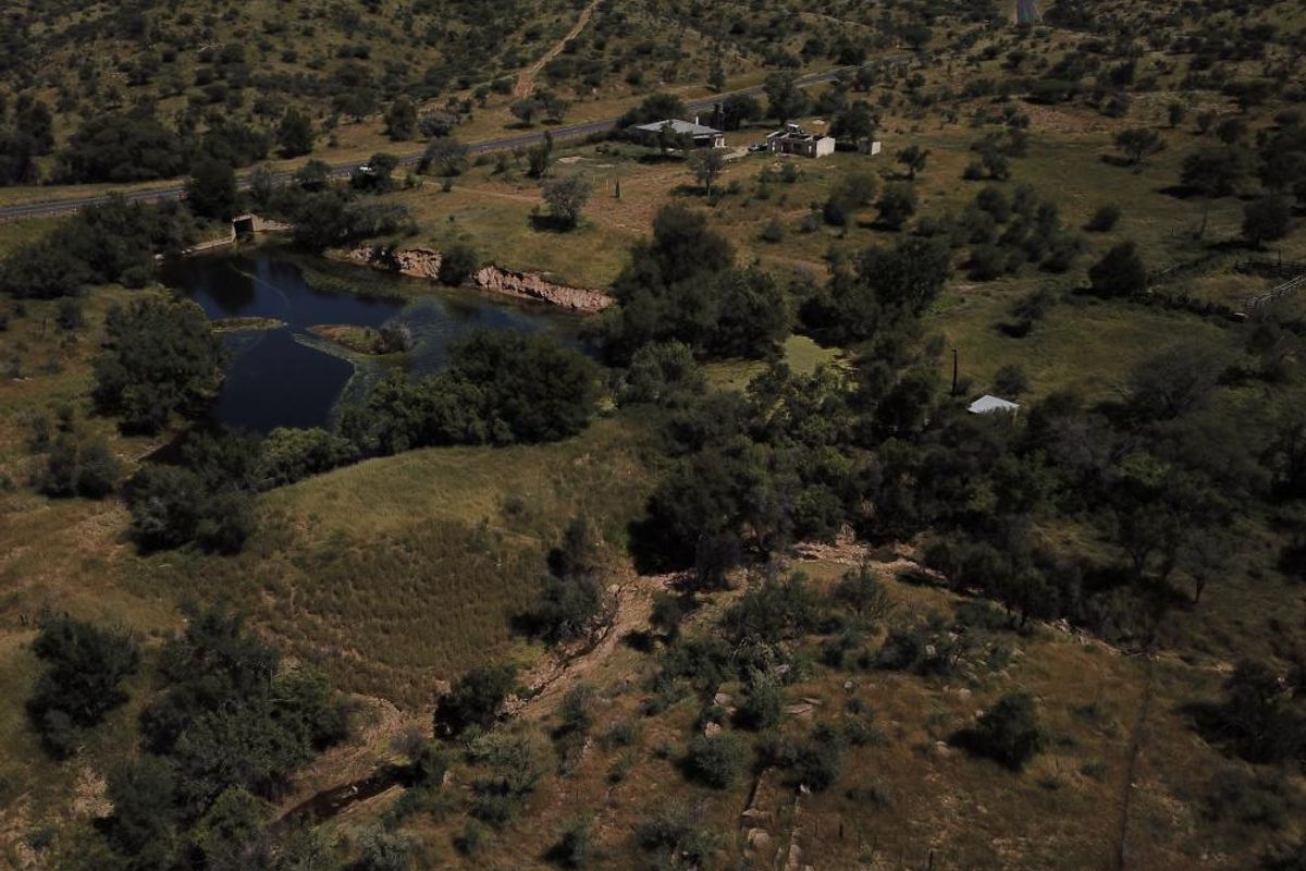 An aerial view of a rural property featuring natural landscape, vegetation, and a water body.