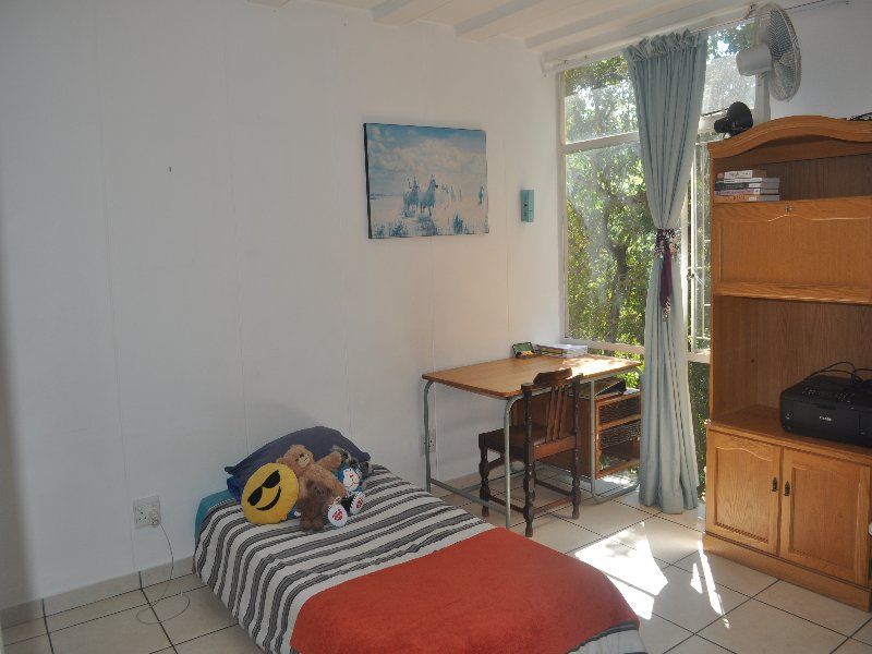A functional bedroom featuring tiled flooring and a large window that provides natural light and garden views.