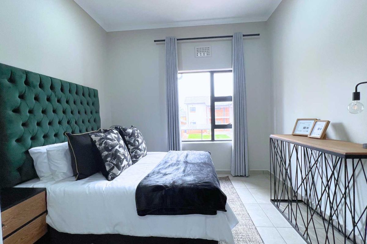 A well-maintained bedroom featuring tiled flooring, neutral wall finishes, and a large window providing natural light.