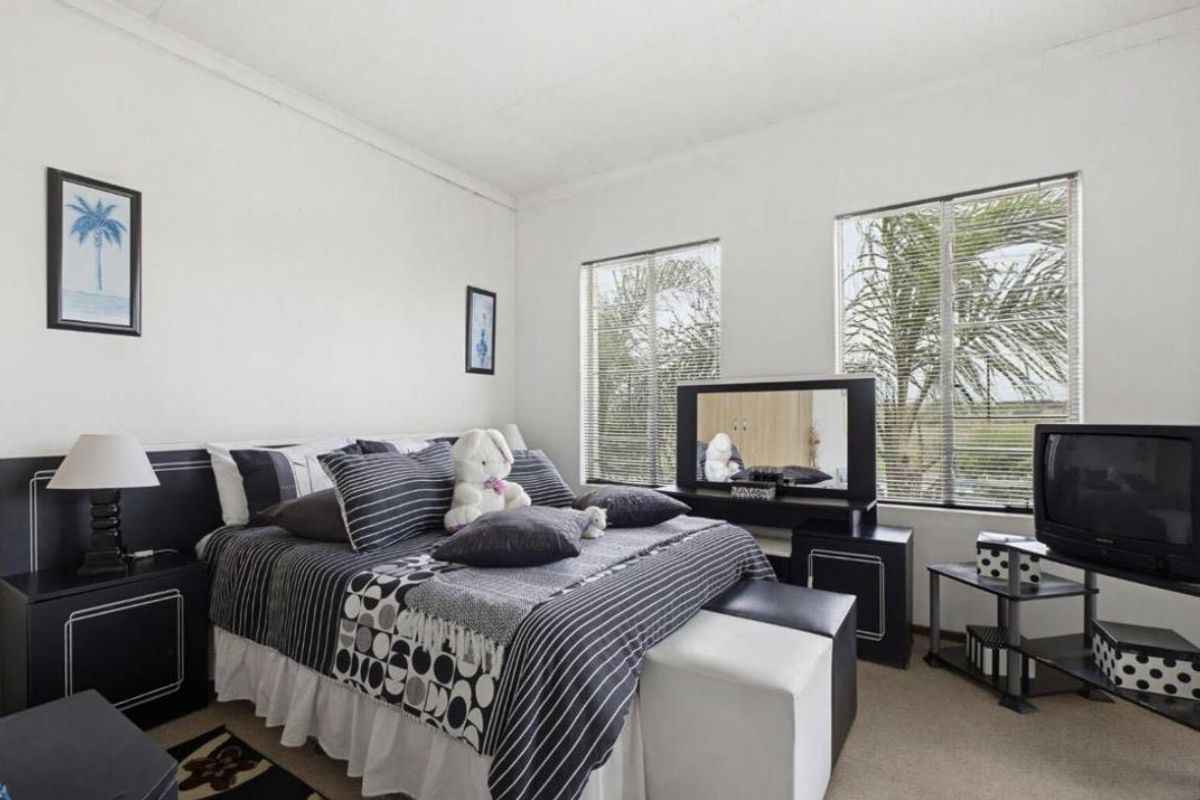 A bedroom featuring neutral walls, carpeted flooring, and dual windows with fitted blinds providing natural light.