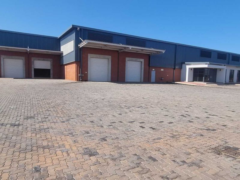 Industrial warehouse facility featuring multiple roller shutter doors, loading bays, and a spacious paved yard area for logistics and vehicle access.