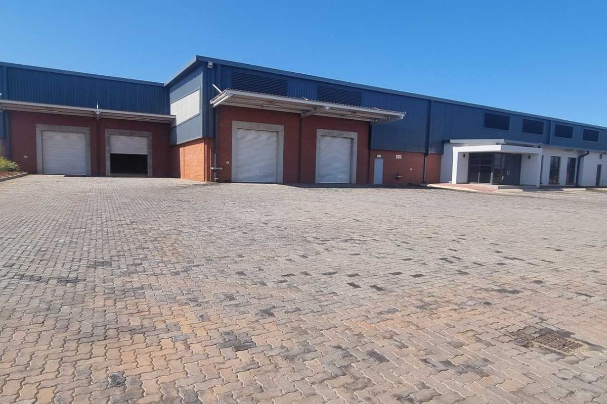 Industrial warehouse facility featuring multiple roller shutter doors, loading bays, and a spacious paved yard area for logistics and vehicle access.