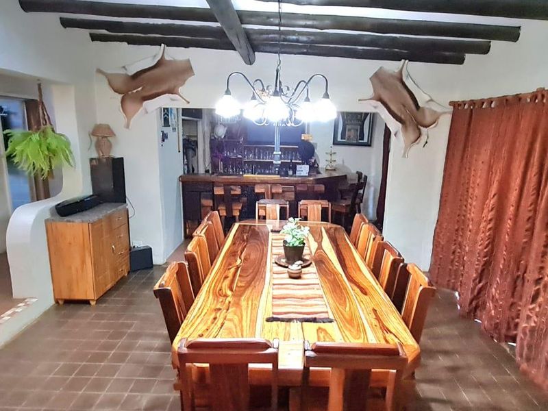 Spacious dining room featuring exposed timber ceiling beams, tiled flooring, and an integrated built-in bar area, perfect for entertaining.