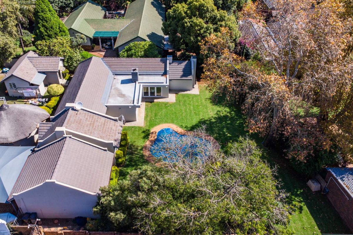 Aerial view of the property showcasing the main house, rear garden, swimming pool, and surrounding landscape.