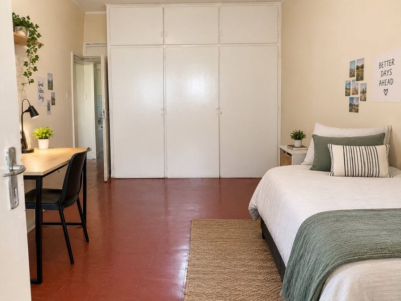 A well-lit bedroom featuring built-in cupboards and durable tiled flooring, offering a functional and comfortable living space.
