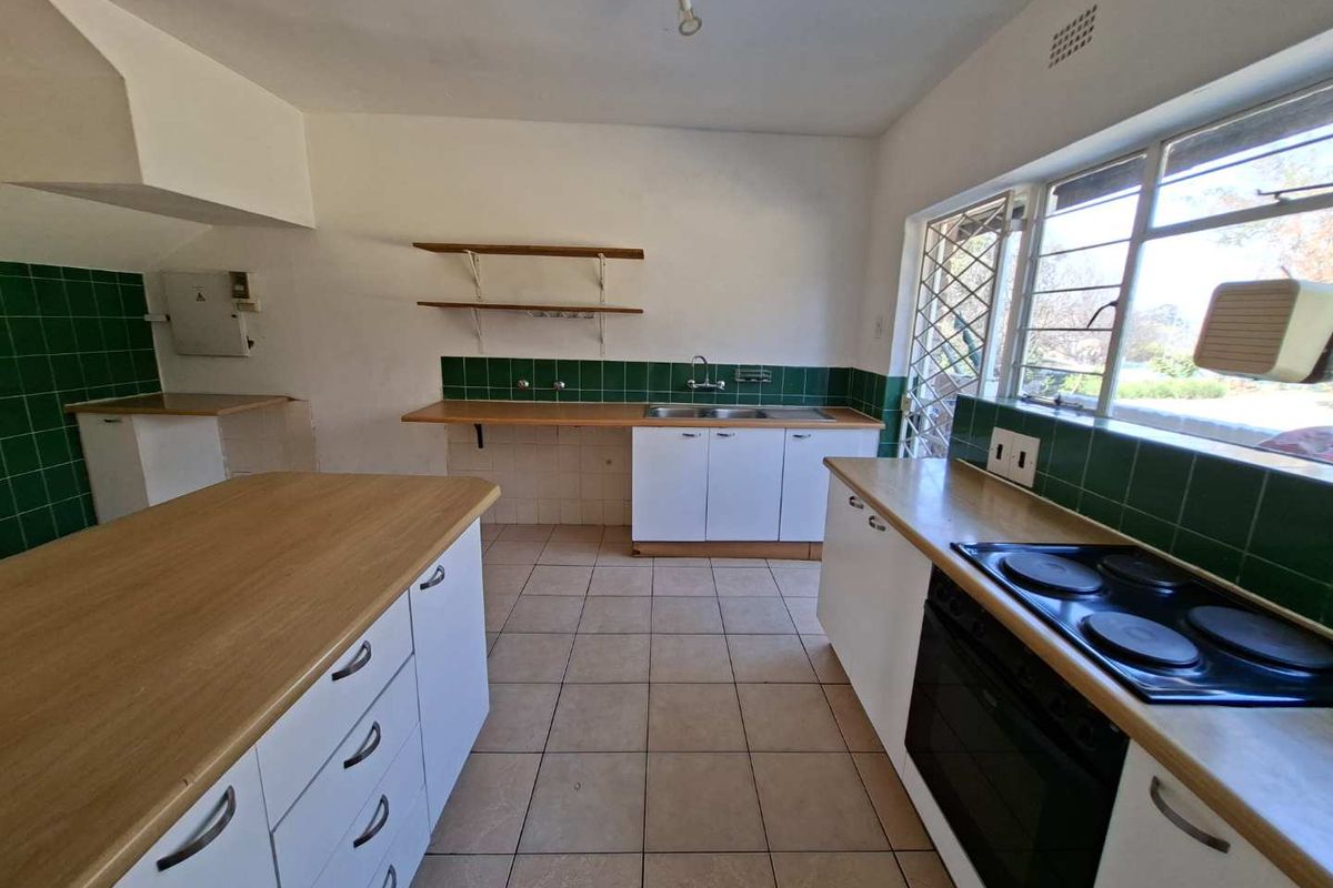 A functional kitchen featuring built-in cabinetry, laminate countertops, an electric hob, and an oven, with ceramic tiling throughout.