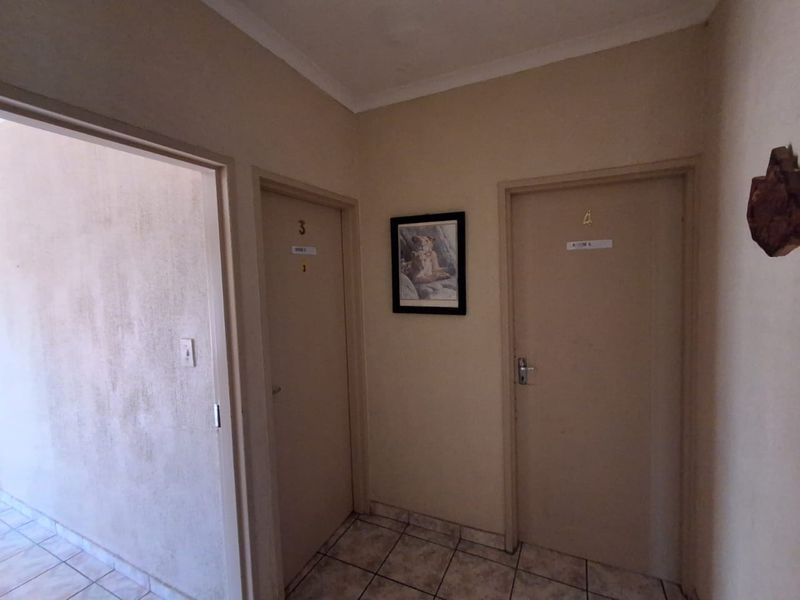 A functional hallway area featuring tiled flooring and access to multiple rooms, showing signs of wear on the wall surfaces.