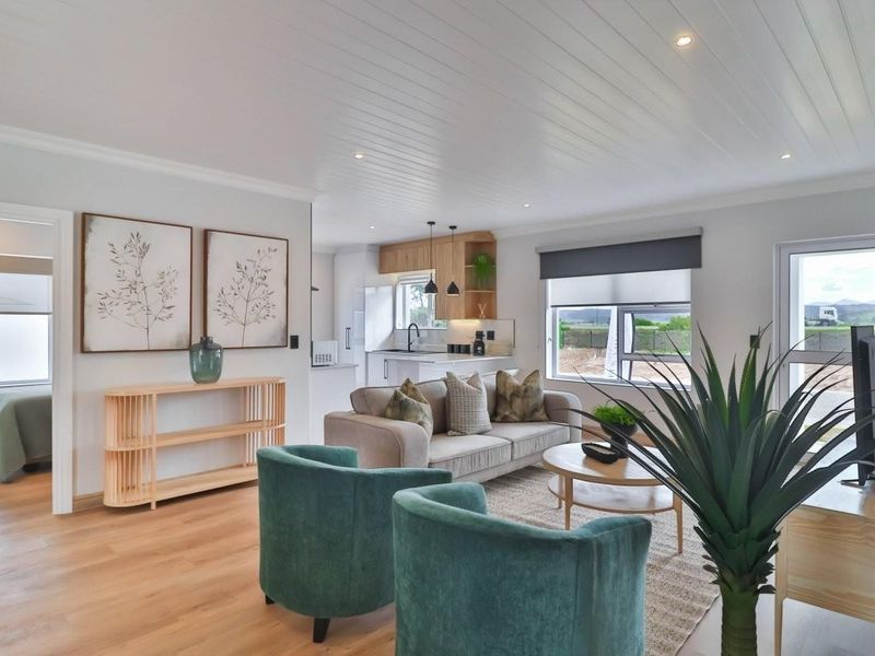 Bright open-plan living area featuring timber flooring, tongue and groove ceiling, recessed lighting, and a modern kitchen with integrated cabinetry.