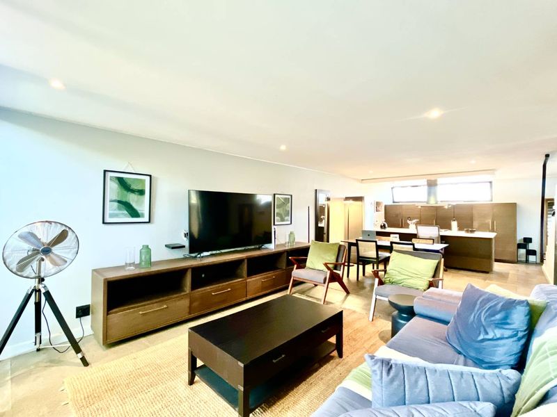 Spacious open-plan living area featuring a modern kitchen with island and integrated cabinetry, seamlessly flowing into the comfortable lounge space.