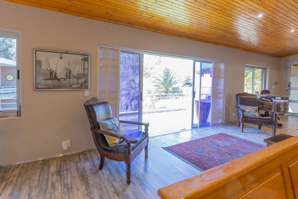 A living room featuring timber tongue and groove ceilings, laminate flooring, and sliding glass doors providing access to an outdoor area.
