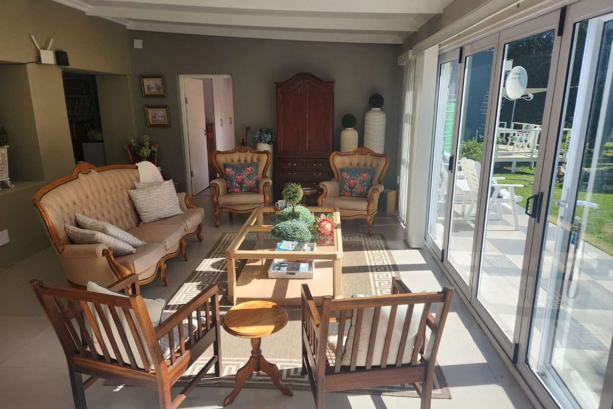A bright, spacious living room featuring large glass stacker doors that open onto the garden, providing excellent natural light and indoor-outdoor flow.