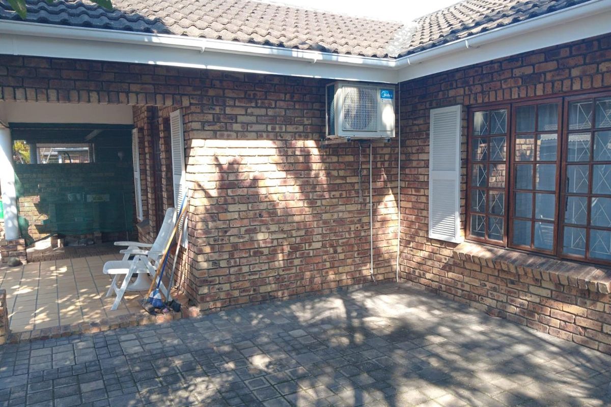 Rear exterior view of the apartment featuring a paved patio area, face brick facade, and installed air conditioning unit.