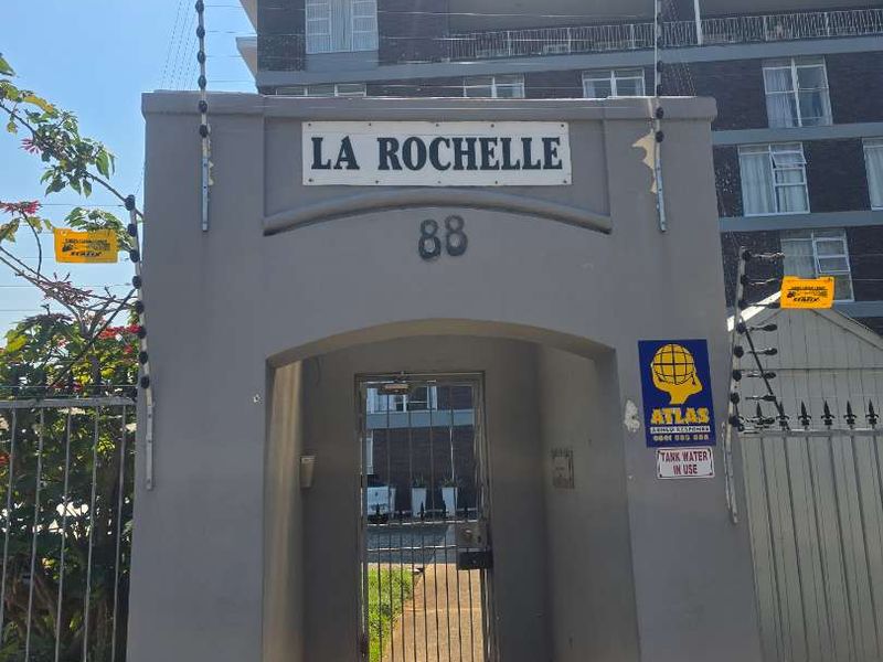 Front pedestrian entrance to La Rochelle apartment complex featuring a secure gate and electric fencing.