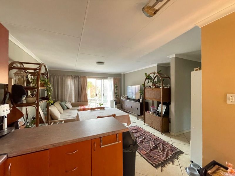 Open-plan living and kitchen area featuring tiled flooring, sliding door access to the exterior, and functional kitchen cabinetry.
