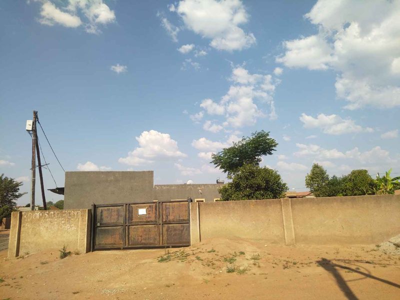 Front exterior view of the property featuring a perimeter wall and metal gate entrance.