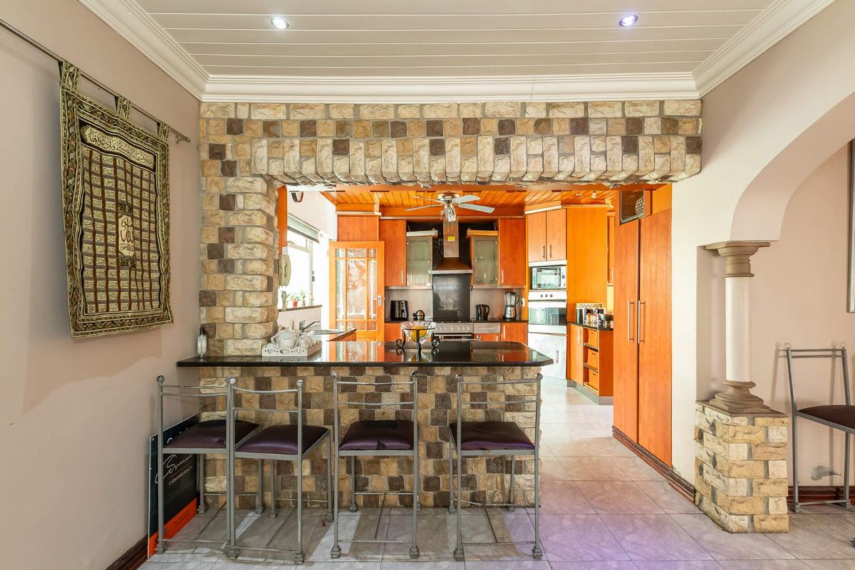 A kitchen featuring a stone-clad breakfast bar with granite countertop, built-in wooden cabinetry, integrated oven, and recessed lighting.