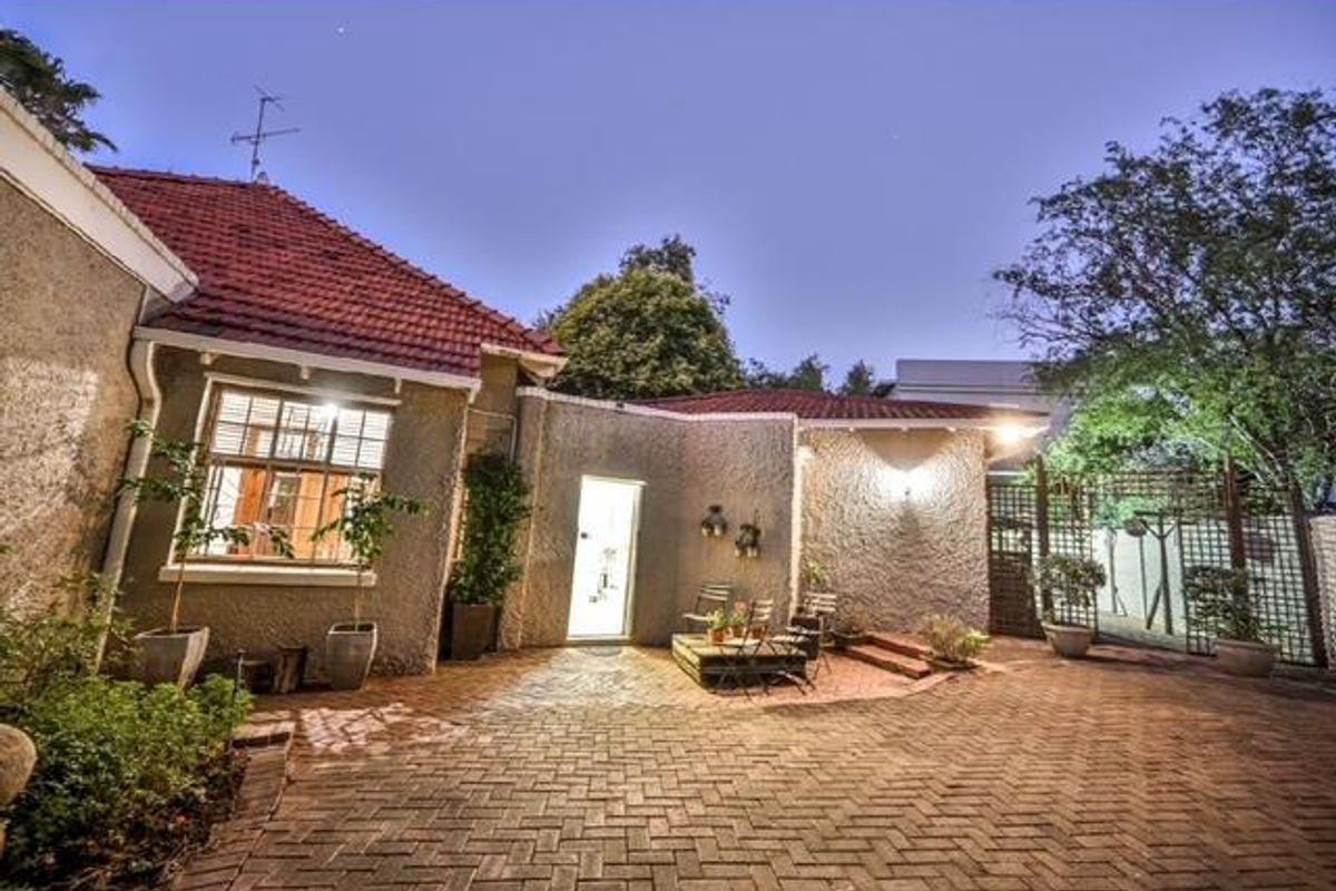 A well-maintained rear courtyard featuring brick paving, stucco exterior walls, and terracotta roof tiles, providing a private outdoor entertainment space.