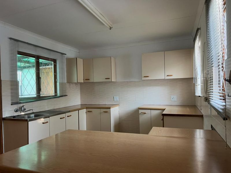 A functional, empty kitchen featuring built-in cabinetry, laminate countertops, and a stainless steel sink, offering a blank canvas for modern renovation.