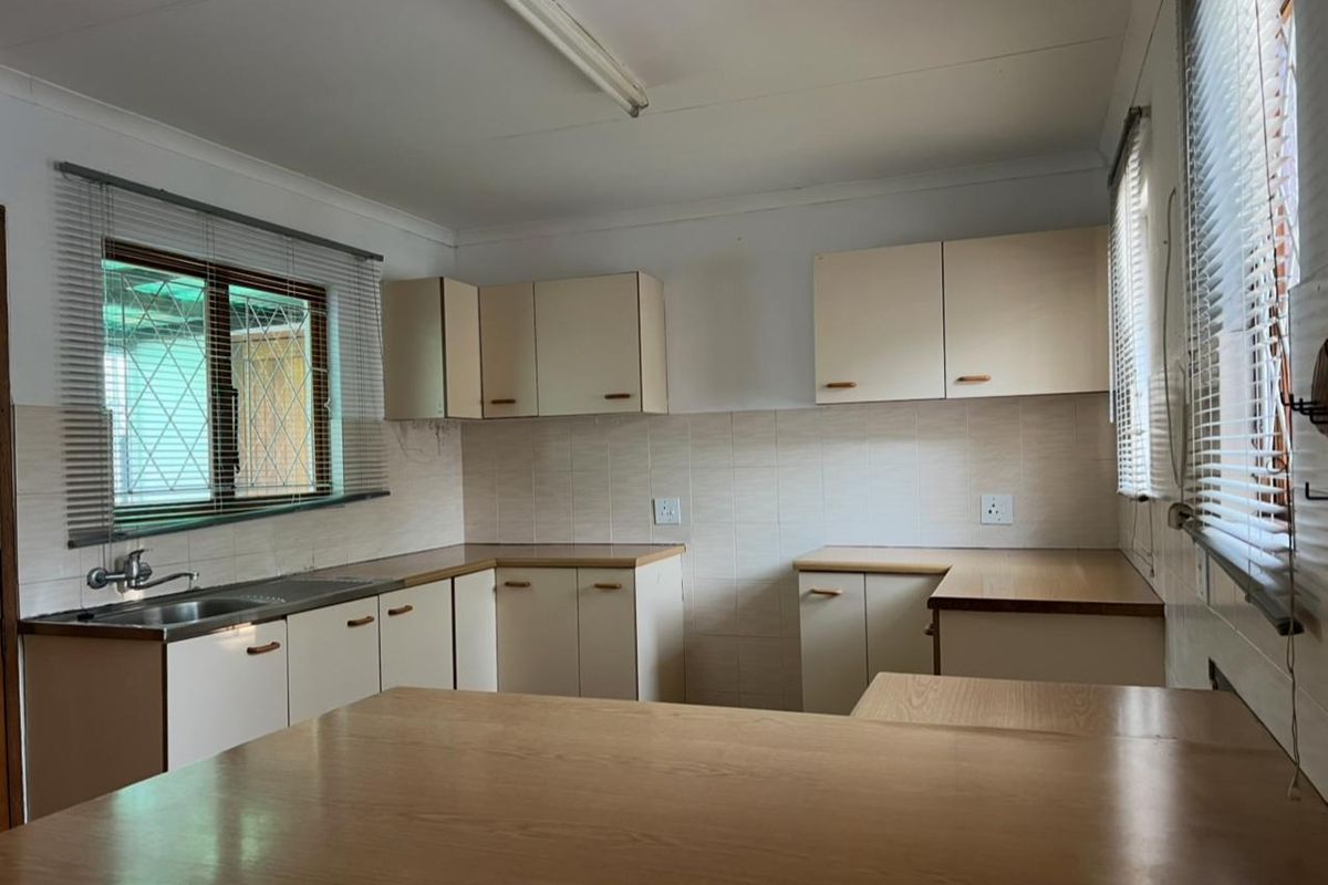 A functional, empty kitchen featuring built-in cabinetry, laminate countertops, and a stainless steel sink, offering a blank canvas for modern renovation.