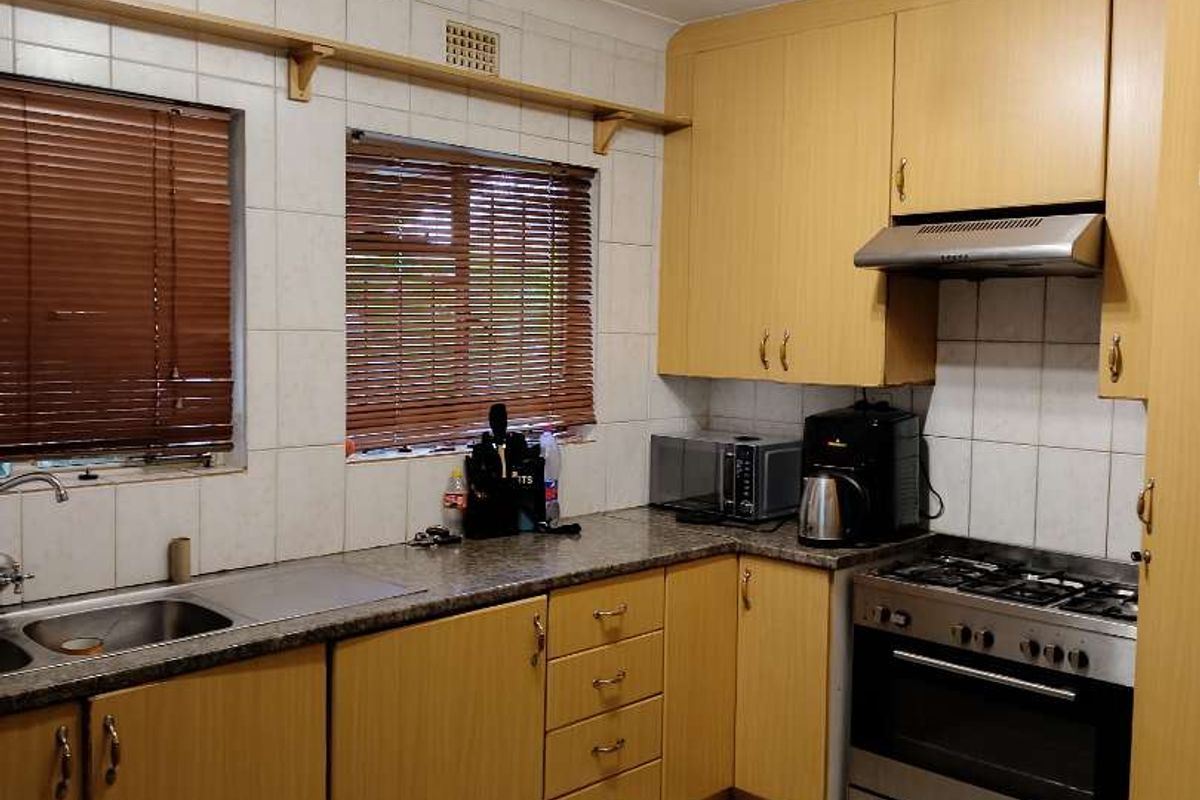Functional kitchen featuring laminate cabinetry, granite-look countertops, gas hob, built-in oven, extractor fan, and tiled flooring with a neutral splashback.