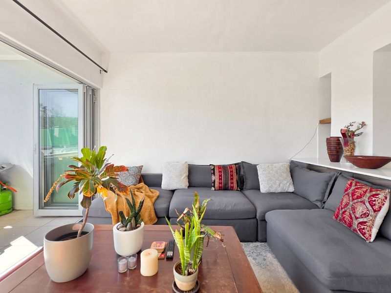 A bright living room featuring a large sliding glass door that opens to an outdoor area, with neutral walls and a built-in shelf.