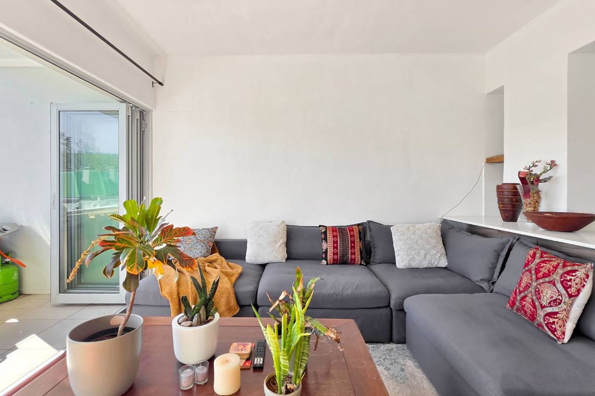A bright living room featuring a large sliding glass door that opens to an outdoor area, with neutral walls and a built-in shelf.