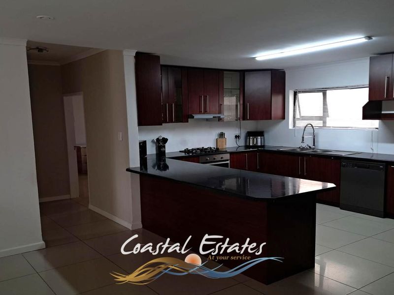 A functional kitchen featuring dark wood cabinetry, granite countertops, a built-in oven, gas hob, and tiled flooring.