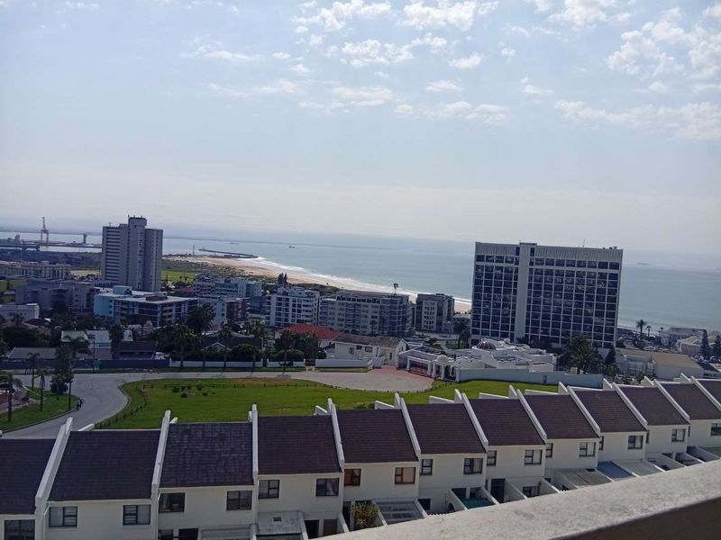 Elevated coastal view overlooking the surrounding residential neighborhood, urban landscape, and the nearby beach and ocean.