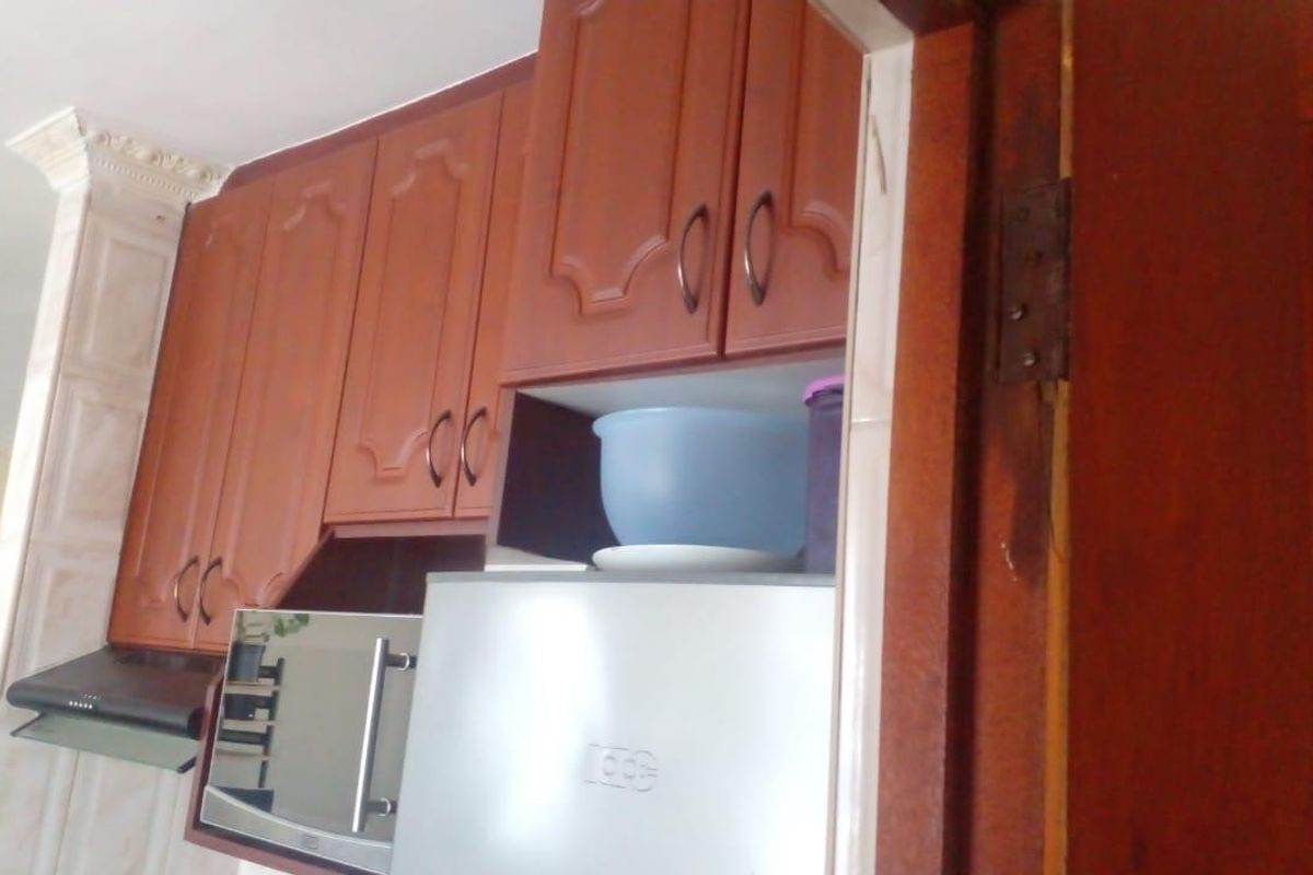 A kitchen area featuring traditional wooden cabinetry, a built-in extractor fan, and a tiled pillar detail.