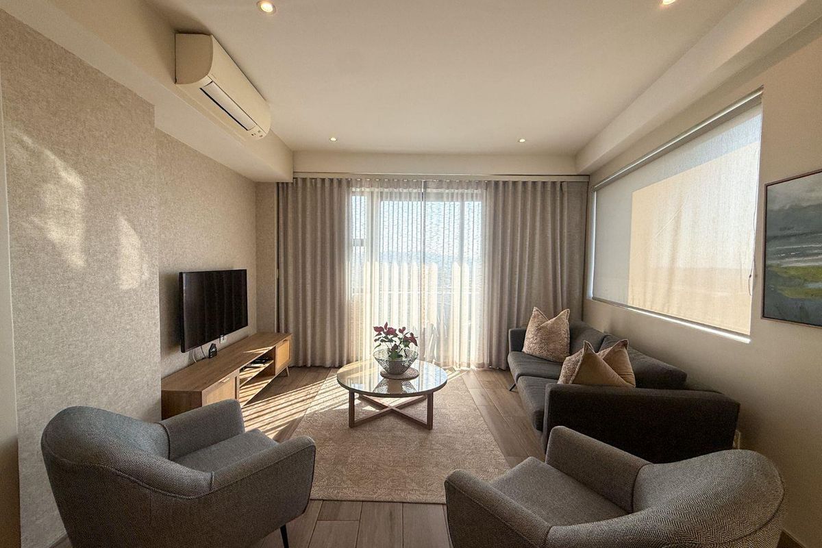 A well-maintained living room featuring tiled flooring, recessed downlighting, and a wall-mounted split-system air conditioner, offering a comfortable and modern living space.