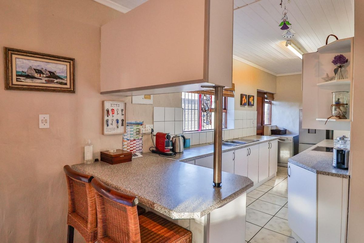 A functional kitchen featuring a breakfast bar, laminate countertops, white cabinetry, and tiled flooring, providing a practical layout for daily meal preparation.
