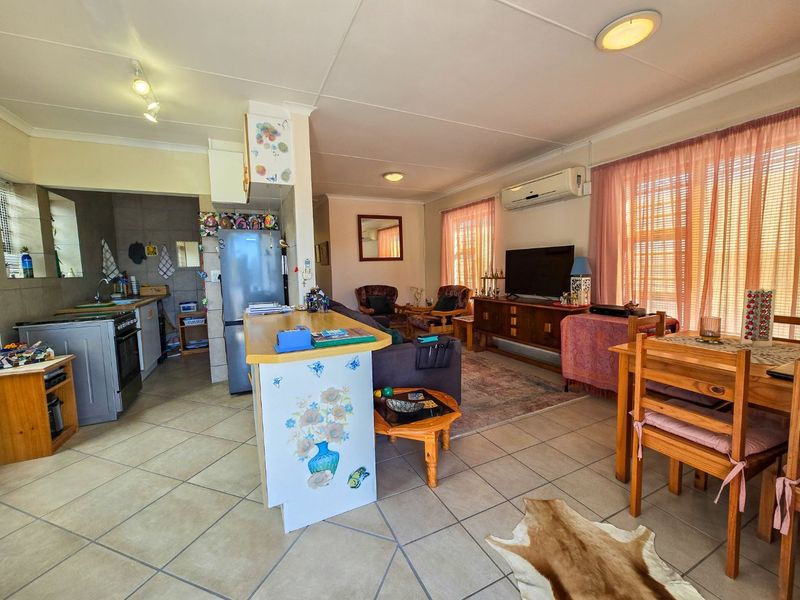Open-plan living area featuring a functional kitchen with built-in cabinetry, tiled flooring throughout, and a split-system air conditioner for climate control.
