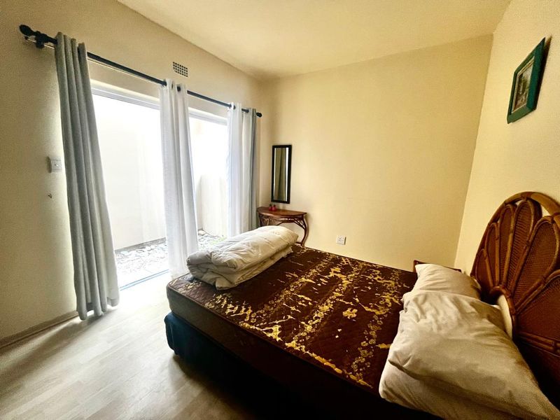 A bedroom featuring laminate flooring and a large sliding glass door providing access to an outdoor area.