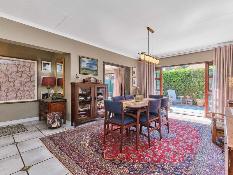 Spacious dining room featuring tiled flooring, modern pendant lighting, and large sliding glass doors providing seamless access to the outdoor patio area.
