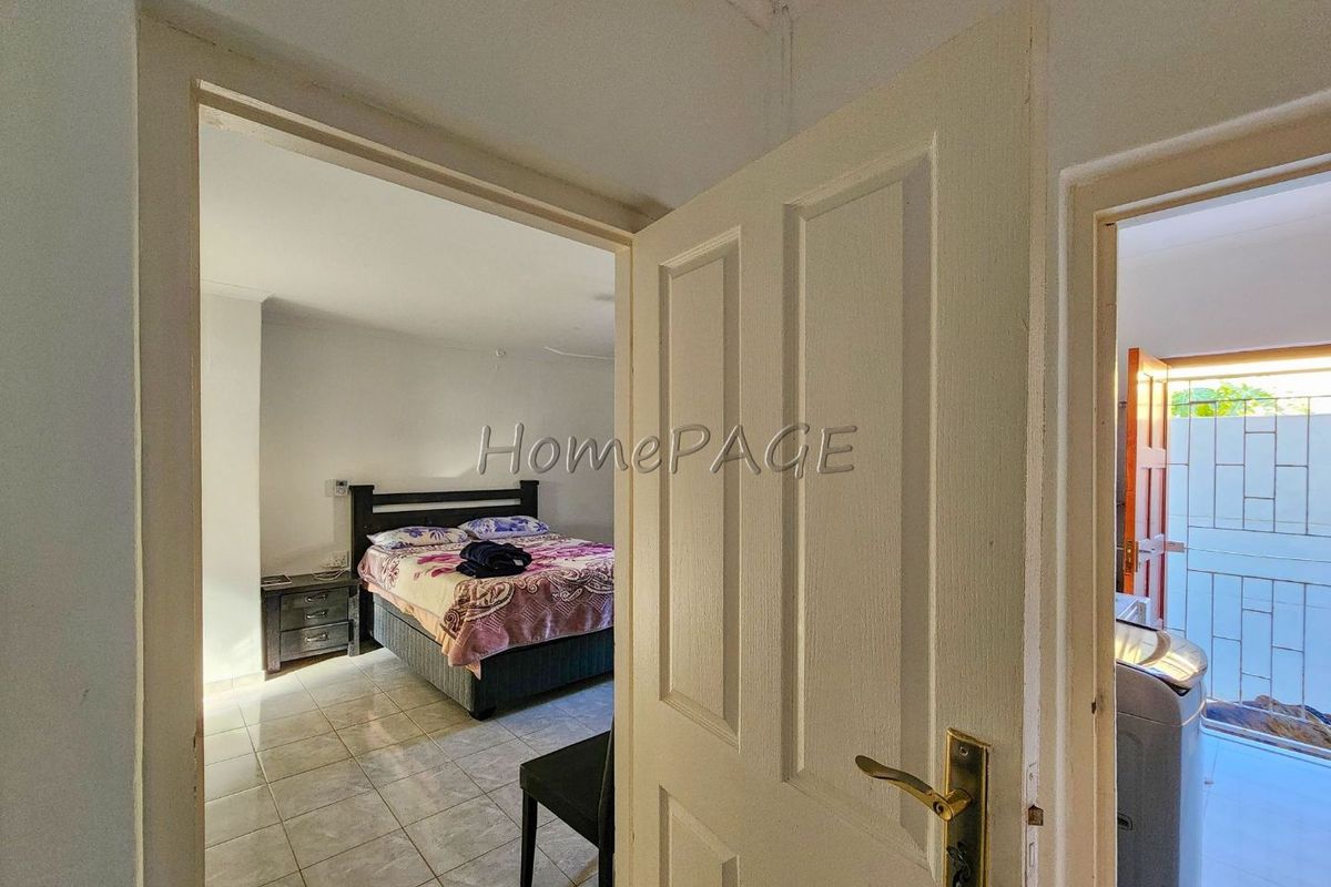 View through a doorway into a bedroom with tiled flooring, featuring a neutral interior layout.