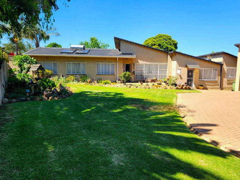 A well-maintained single-story house featuring a paved driveway, solar water heating system, and a neatly landscaped front garden.