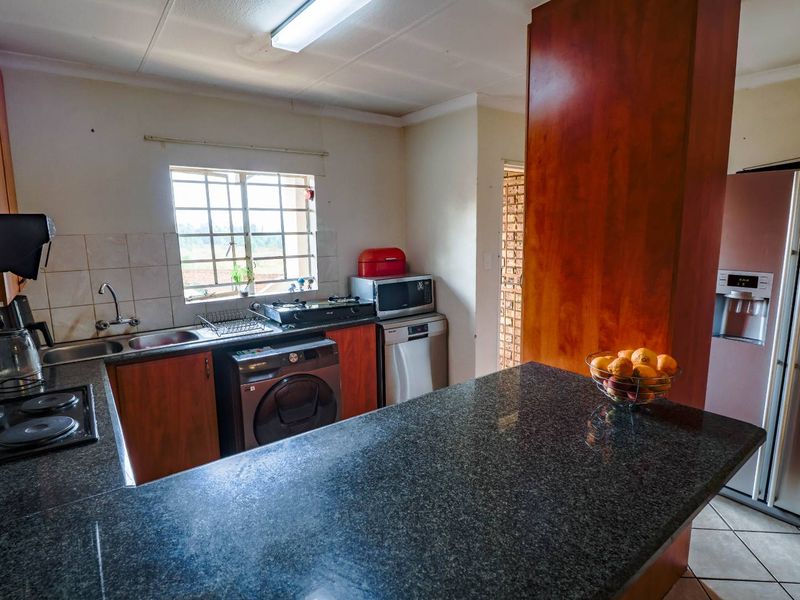Functional kitchen featuring granite countertops, ample cabinetry, and a tiled backsplash, offering a practical layout for daily meal preparation.