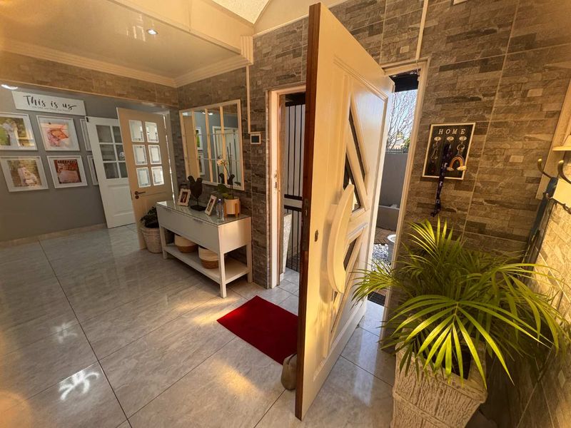 Welcoming entrance hall featuring polished tiled flooring and a textured stone veneer feature wall, leading to internal living spaces.