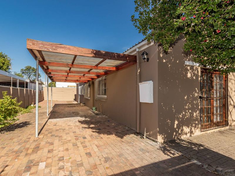 A paved outdoor patio area featuring a timber pergola with corrugated roofing, providing a functional space for outdoor use.