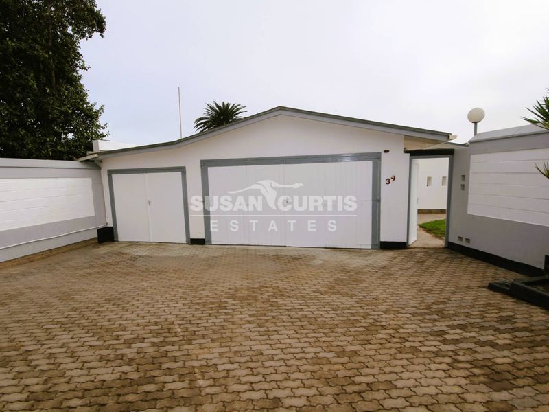 Front exterior view of the property featuring a paved driveway, double and single garage doors, and a secure boundary wall.