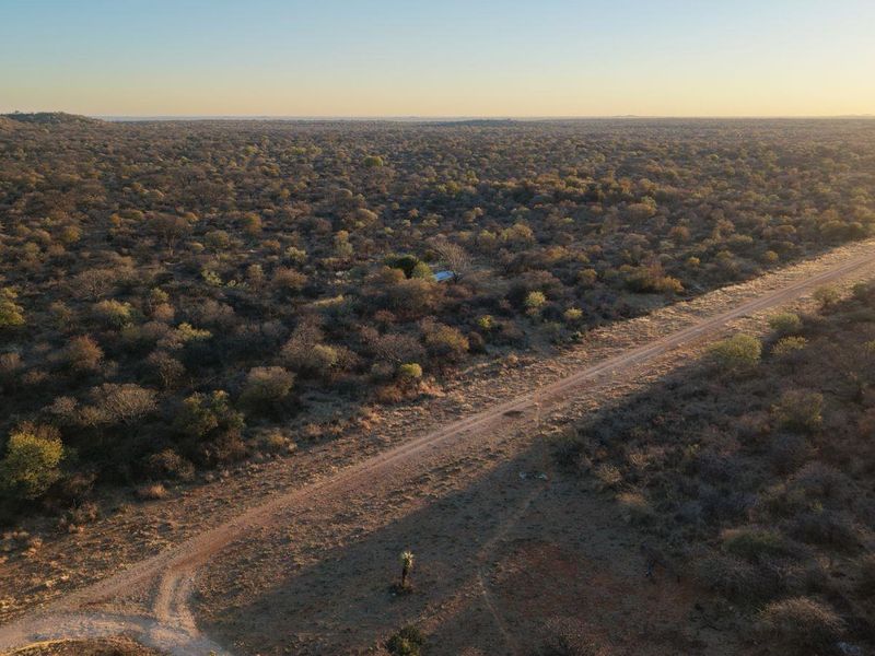 An expansive aerial view of the lodge property, showcasing the vast surrounding bushveld landscape and the access road.