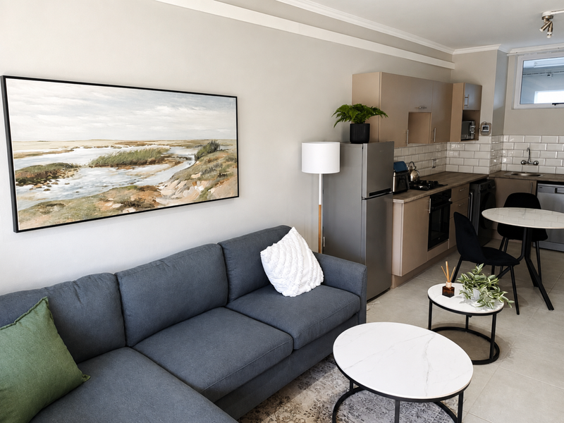 A well-maintained open-plan living and kitchen area featuring modern cabinetry, subway tile backsplash, and neutral tiled flooring.