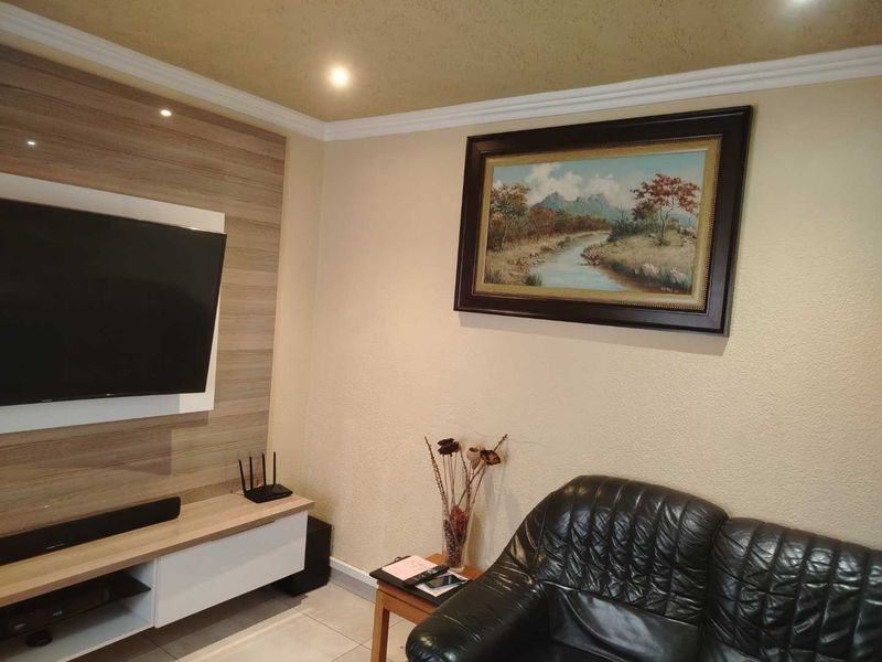 A living room featuring a built-in media unit, recessed downlighting, crown molding, and tiled flooring.