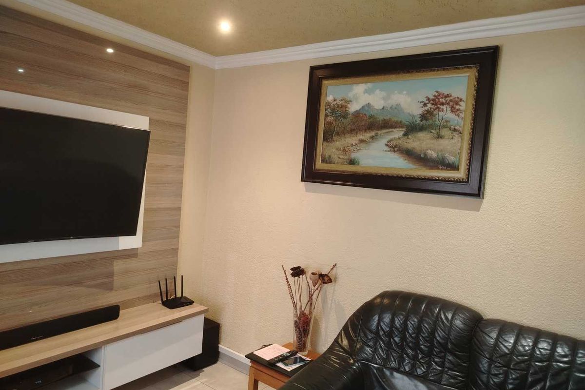 A living room featuring a built-in media unit, recessed downlighting, crown molding, and tiled flooring.