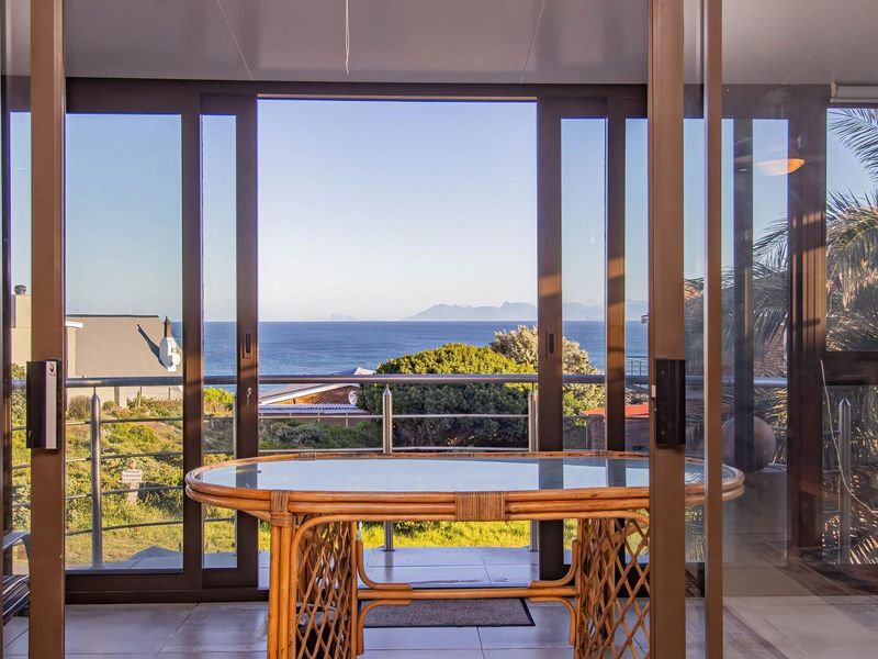 A bright enclosed patio featuring large sliding glass doors that offer expansive ocean and mountain views.