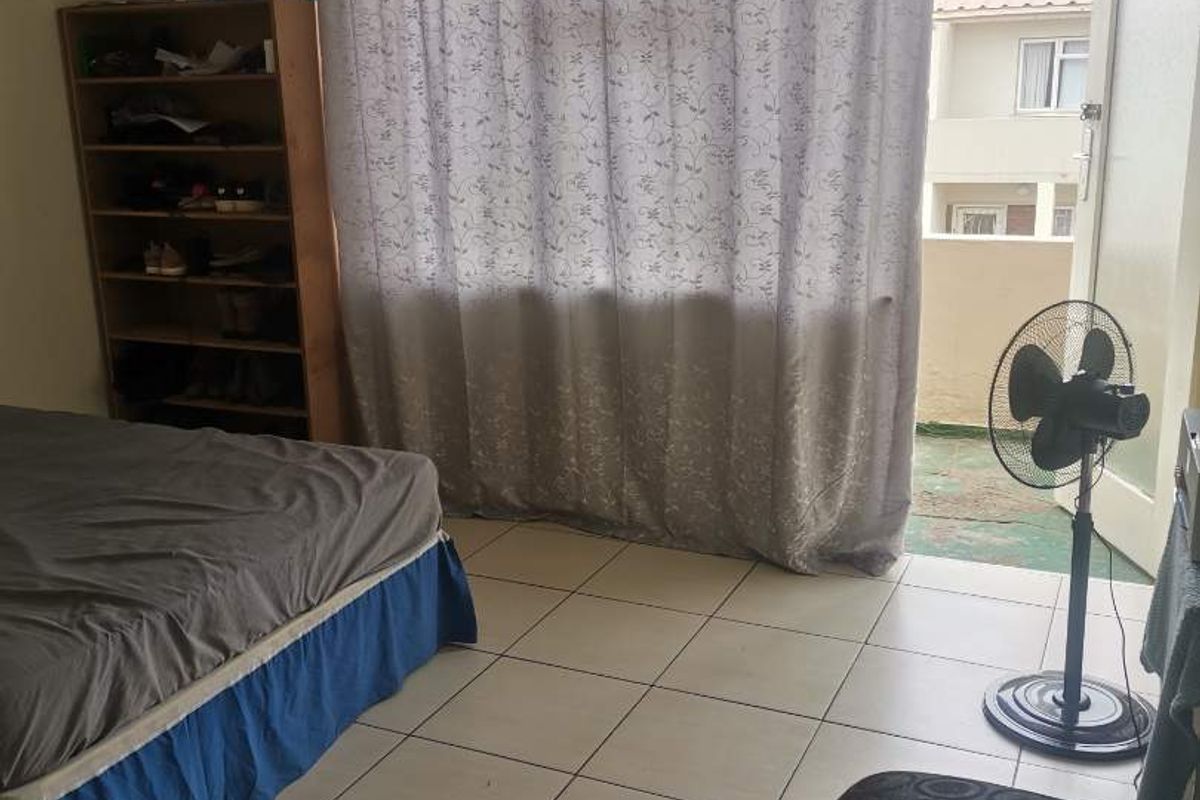 A bedroom featuring tiled flooring and direct access to an outdoor balcony area through a glass door.