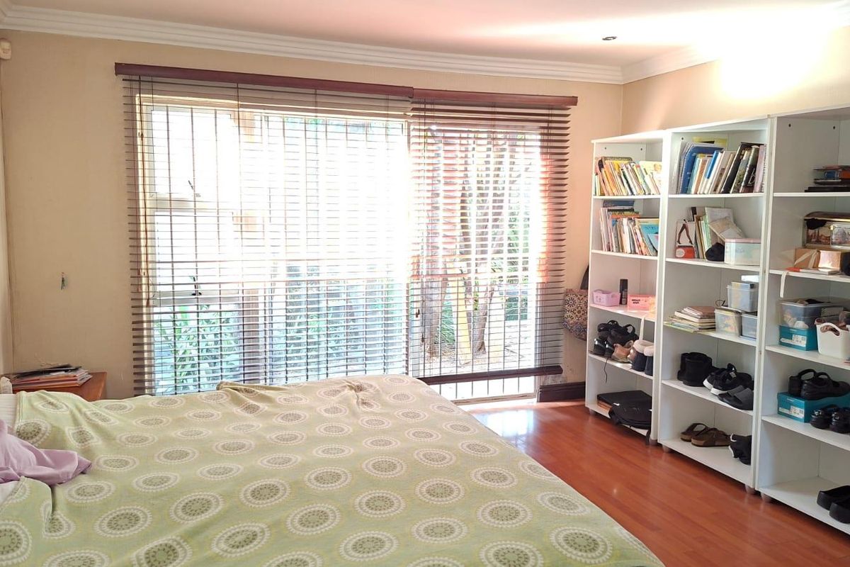 A bedroom featuring laminate flooring, cornicing, and a sliding glass door with venetian blinds providing access to the exterior.