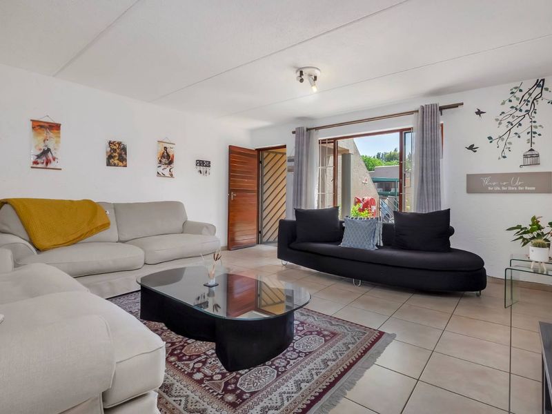 A bright living room featuring tiled flooring, a ceiling light fixture, and direct access to an outdoor area through a sliding glass door.