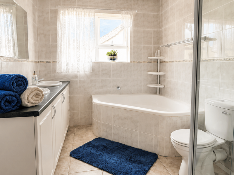 A functional bathroom featuring a corner bathtub, a separate glass-enclosed shower, a vanity with a basin, and full-height wall tiling.
