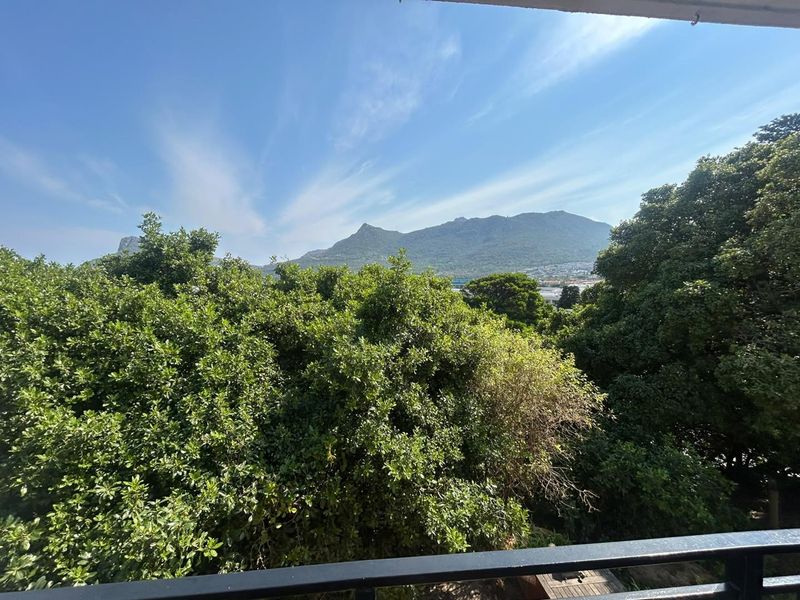 A scenic view of the surrounding mountains and lush greenery, captured from an elevated balcony with a black metal railing.